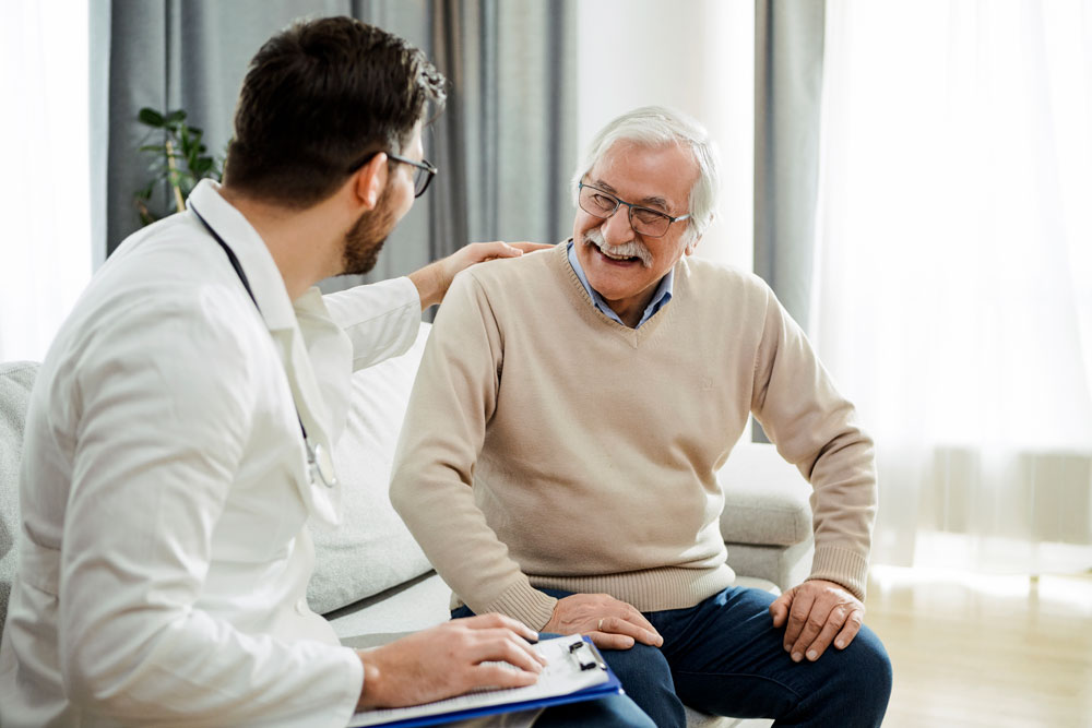 Äldre manlig patient som skrattar med en läkare