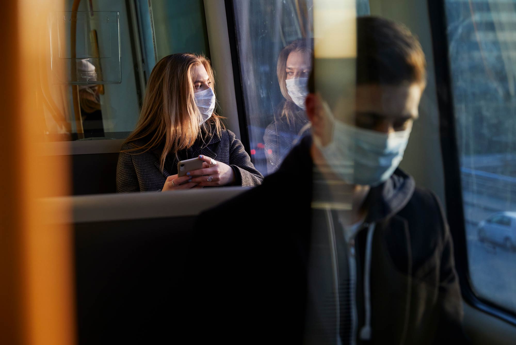 Woman sitting on bus wearing protective mask