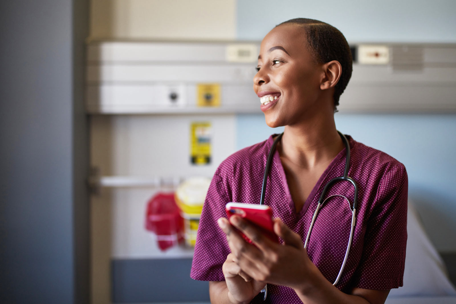 Glad sjuksköterska som håller i en mobiltelefon